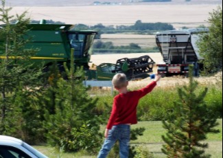 Boy waving at a combine